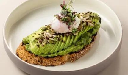 Avocado toast topped with a poached egg, seeds and micro herbs