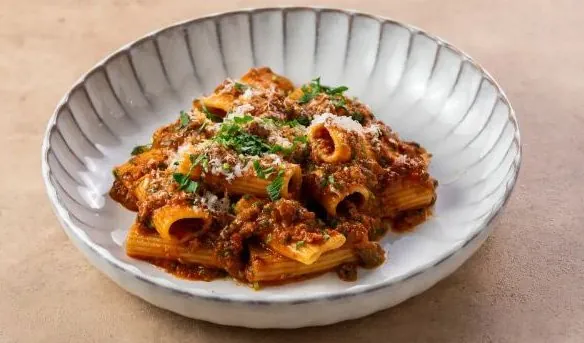Rigatoni Bolognese with parmesan in a ridged stoneware bowl