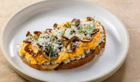 Truffle scramble toast with roasted mushrooms and grated cheese on multigrain bread