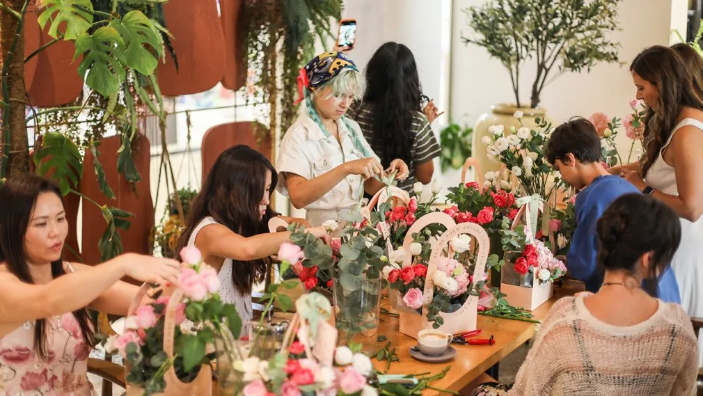 Guests arranging flowers around a long table during a workshop